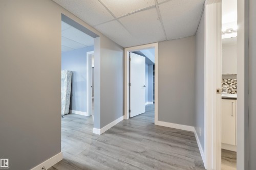 Contemporary interior hallway featuring wood-finish flooring, light gray walls, and white trim - 6134 37A Avenue, Edmonton, AB 