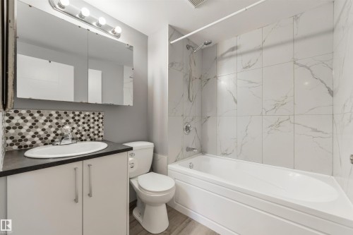 Bathroom featuring a white vanity cabinet with dark countertop, oval undermount sink, and mosaic tile backsplash - 6134 37A Avenue, Edmonton, AB 