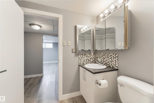 Bathroom vanity with integrated sink, mosaic tile backsplash, and mirrored medicine cabinets - 6134 37A Avenue, Edmonton, AB 