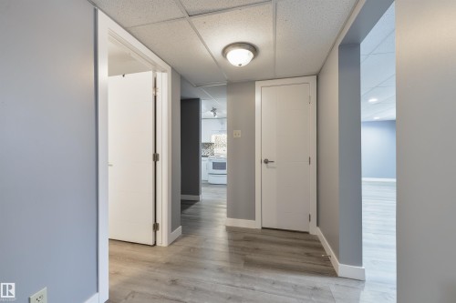 Hallway featuring wood-finish flooring, white baseboards, and a neutral wall color - 6134 37A Avenue, Edmonton, AB 