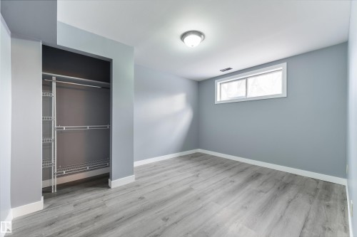 Room featuring wood-finish flooring, a window with white trim, and a built-in closet with wire shelving - 6134 37A Avenue, Edmonton, AB 