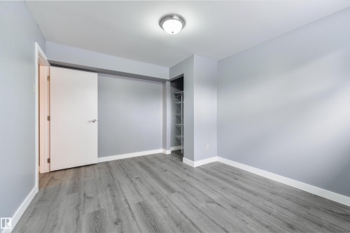Room featuring wood-finish flooring, light gray walls, white baseboards, and a flush mount ceiling light fixture - 6134 37A Avenue, Edmonton, AB 