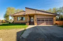 Brick exterior featuring an integrated garage with a panel door, concrete driveway, and covered front entry - 6134 37A Avenue, Edmonton, AB 