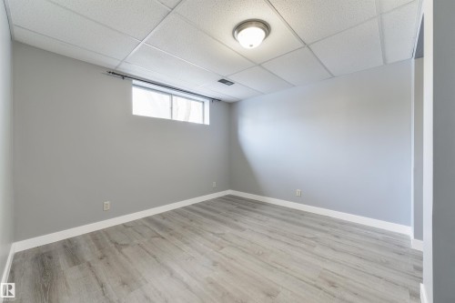 Room featuring wood-finish flooring, light grey painted walls, white baseboards, and a drop ceiling with recessed lighting - 6134 37A Avenue, Edmonton, AB 