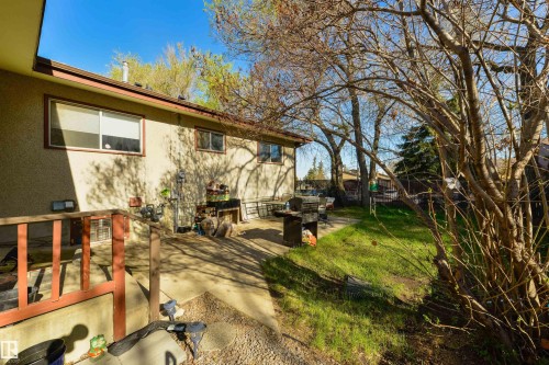Expansive rear yard featuring a concrete patio, a green lawn area, and mature trees providing natural screening - 6134 37A Avenue, Edmonton, AB 