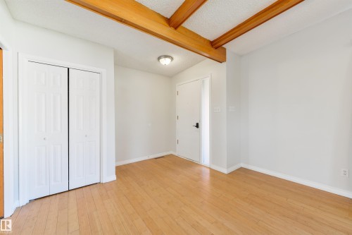Room featuring wood-finish flooring, exposed wood beams, and a popcorn ceiling - 6134 37A Avenue, Edmonton, AB 