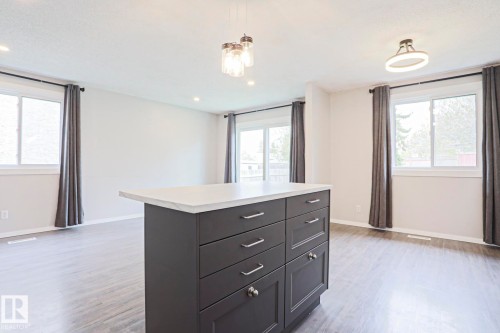 Kitchen island featuring dark cabinetry, silver hardware, and a light-toned countertop - 35 Chungo Drive, Devon, AB - Indoor