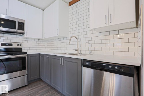 Corner kitchen featuring white shaker upper cabinetry and gray shaker lower cabinetry - 35 Chungo Drive, Devon, AB - Indoor Photo Showing Kitchen With Double Sink With Upgraded Kitchen
