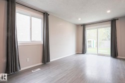 Spacious room featuring wood-finish flooring, light neutral walls, and recessed lighting - 