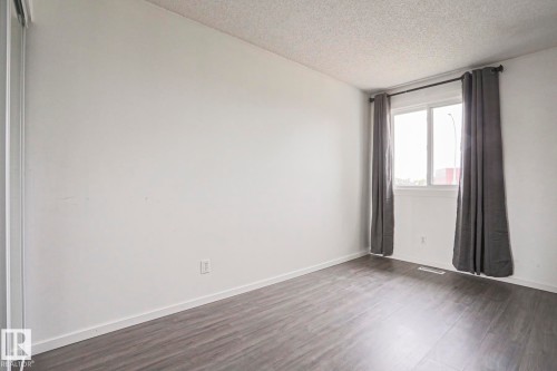 Bright interior room featuring wood-finish flooring, white walls, and a window with a white frame - 35 Chungo Drive, Devon, AB - Indoor Photo Showing Other Room