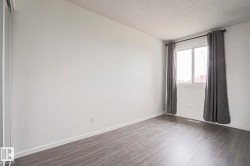 Bright interior room featuring wood-finish flooring, white walls, and a window with a white frame - 