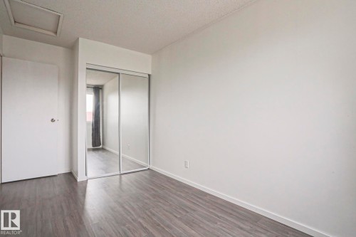 Light-filled room featuring wood-finish flooring, white baseboards, and a mirrored sliding closet door - 35 Chungo Drive, Devon, AB - Indoor Photo Showing Other Room