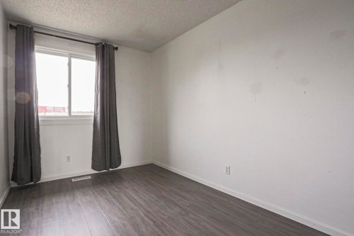 Room featuring wood-finish flooring, a double-hung window with a white frame, and a ceiling-mounted light fixture - 35 Chungo Drive, Devon, AB - Indoor Photo Showing Other Room