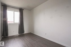 Room featuring wood-finish flooring, a double-hung window with a white frame, and a ceiling-mounted light fixture - 
