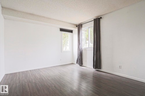 Bright interior space with wood-finish flooring, white walls, and two windows - 35 Chungo Drive, Devon, AB - Indoor Photo Showing Other Room