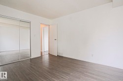 Spacious interior room featuring wood-finish flooring, white walls, and a full-height mirrored closet - 
