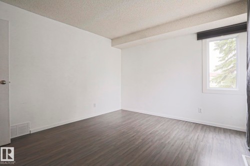 Spacious room featuring wood-finish flooring, white walls, and a textured ceiling - 35 Chungo Drive, Devon, AB - Indoor Photo Showing Other Room
