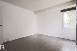 Spacious room featuring wood-finish flooring, white walls, and a textured ceiling - 