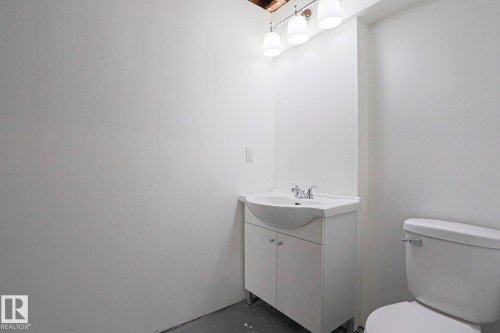 Compact bathroom featuring a white vanity with integrated sink, chrome faucet, and a wall-mounted light fixture with three sconces - 35 Chungo Drive, Devon, AB - Indoor Photo Showing Bathroom