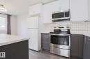 Modern kitchen featuring two-tone cabinetry with white upper cabinets and dark gray lower cabinets - 35 Chungo Drive, Devon, AB  - Indoor Photo Showing Kitchen 