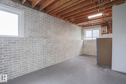 Exposed ceiling joists with visible electrical wiring and conduit, concrete flooring, and light-colored brick-patterned walls - 35 Chungo Drive, Devon, AB - Indoor