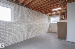 Exposed ceiling joists with visible electrical wiring and conduit, concrete flooring, and light-colored brick-patterned walls - 