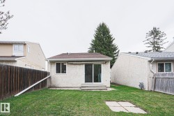 Expansive green lawn with a brown privacy fence and mature trees - 