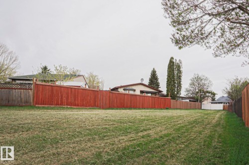Expansive grassy lot with a long, red-stained privacy fence bordering the property - 35 Chungo Drive, Devon, AB - Outdoor