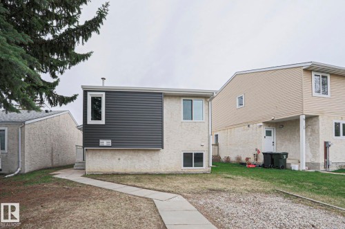 Property exterior featuring stucco siding and dark horizontal paneling, with multiple white-framed windows - 35 Chungo Drive, Devon, AB - Outdoor With Exterior
