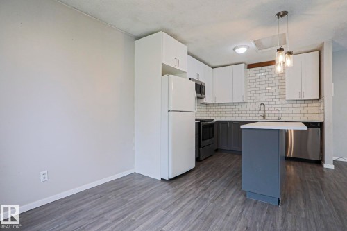 Modern kitchen featuring white upper cabinetry, gray lower cabinetry, and a subway tile backsplash - 35 Chungo Drive, Devon, AB - Indoor Photo Showing Kitchen