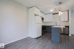Modern kitchen featuring white upper cabinetry, gray lower cabinetry, and a subway tile backsplash - 