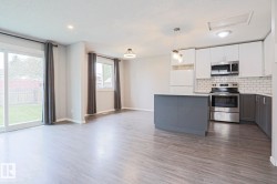 Open-concept living space featuring wood-finish flooring, a kitchen island, stainless steel appliances, subway tile backsplash, and sliding glass door access to the outdoor space - 