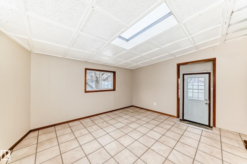 The room features a tiled floor, a window with a brown frame, and a white ceiling with a skylight - 13332 25 Street, Edmonton, AB - Indoor Photo Showing Other Room