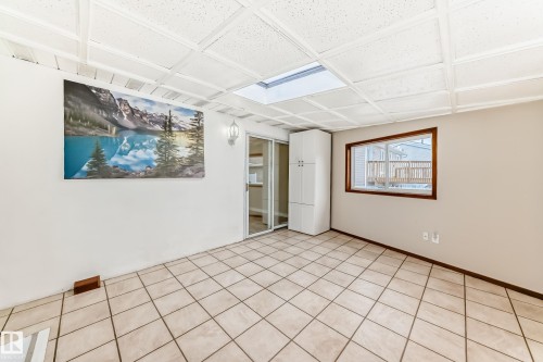 This versatile room features tiled flooring, a skylight, and a window with a wood frame - 13332 25 Street, Edmonton, AB - Indoor Photo Showing Other Room