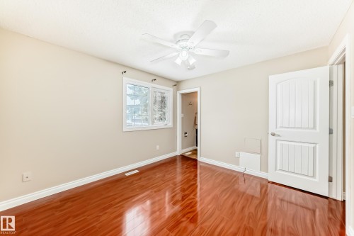 This room features glossy wood flooring, a window offering natural light, and a ceiling fan - 13332 25 Street, Edmonton, AB - Indoor Photo Showing Other Room