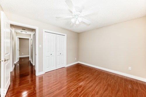 This room features polished hardwood flooring, a ceiling fan, and bi-fold closet doors - 13332 25 Street, Edmonton, AB - Indoor Photo Showing Other Room