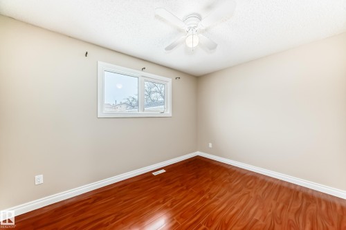 This room features rich hardwood flooring, light-colored walls, and a window providing natural light - 13332 25 Street, Edmonton, AB - Indoor Photo Showing Other Room