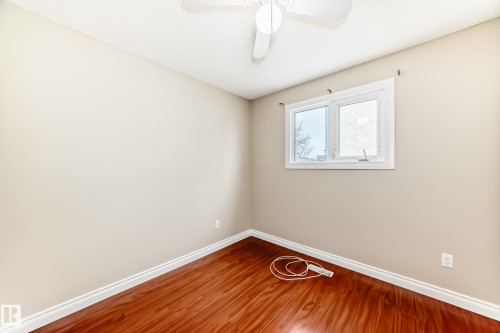 Room featuring hardwood flooring, light-colored walls, a window with white trim, and a white ceiling fan - 13332 25 Street, Edmonton, AB - Indoor Photo Showing Other Room