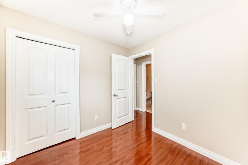The property features a room with hardwood flooring, a ceiling fan, and white baseboards - 13332 25 Street, Edmonton, AB - Indoor Photo Showing Other Room