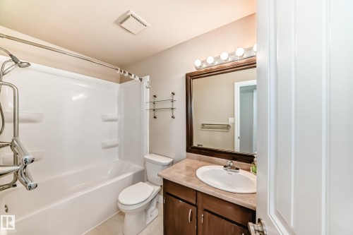 The bathroom features a white bathtub and shower combination with a curved shower rod - 13332 25 Street, Edmonton, AB - Indoor Photo Showing Bathroom