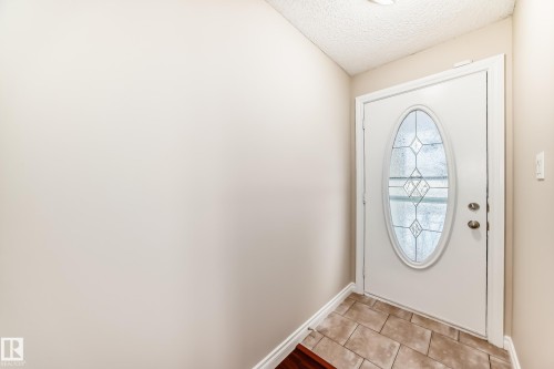 Entryway featuring a white door with an oval-shaped decorative glass insert, complemented by tiled flooring - 13332 25 Street, Edmonton, AB - Indoor Photo Showing Other Room