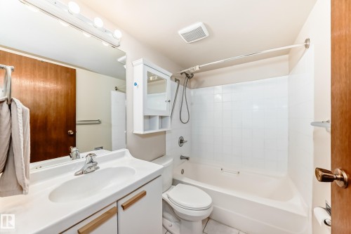 Bathroom featuring a vanity with an integrated sink, a toilet, and a bathtub with a shower - 13332 25 Street, Edmonton, AB - Indoor Photo Showing Bathroom
