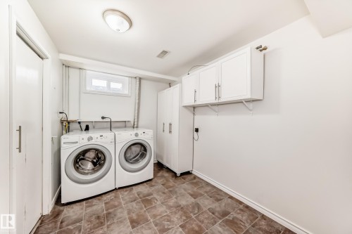 This laundry area features a washer and dryer, practical tiled flooring, and wall-mounted white cabinetry for storage - 13332 25 Street, Edmonton, AB - Indoor Photo Showing Laundry Room