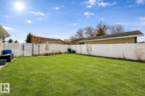 The property features a spacious lawn with a white fence enclosing the yard - 13332 25 Street, Edmonton, AB - Outdoor