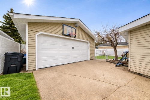 The property features a concrete driveway leading to a garage with a white sectional door, complemented by a basketball hoop - 13332 25 Street, Edmonton, AB - Outdoor With Exterior