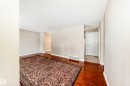 This living area features polished wood flooring, light-toned walls, and a white interior door with vertical paneling - 13332 25 Street, Edmonton, AB  - Indoor Photo Showing Other Room 