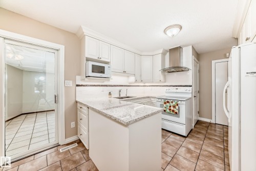 The kitchen features white cabinetry, a white tile backsplash, and light-colored countertops - 13332 25 Street, Edmonton, AB - Indoor Photo Showing Kitchen
