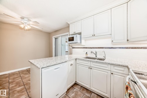 Kitchen featuring white cabinetry, granite countertops, a double basin sink, and a tiled backsplash - 13332 25 Street, Edmonton, AB - Indoor Photo Showing Kitchen