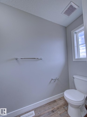 Powder room featuring light gray walls, white baseboards, and wood-finish flooring - 11 165 Cy Becker Boulevard, Edmonton, AB - Indoor Photo Showing Bathroom