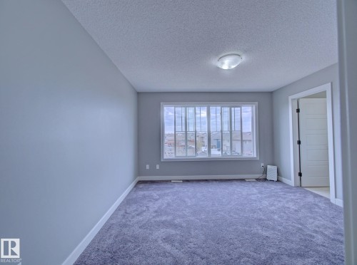 Spacious room featuring broadloom carpeting and light gray wall paint - 11 165 Cy Becker Boulevard, Edmonton, AB - Indoor Photo Showing Other Room